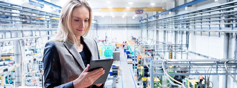 woman looking at tablet standing in manufacturing building