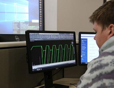 person working at a computer looking at mechanical charts