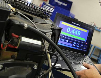 person working with engine or machine with laptop computer