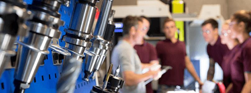students in a machine shop with drill press in foreground