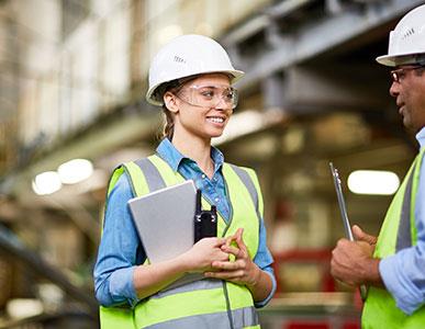 two people in yellow safety vests and white hardhats talking