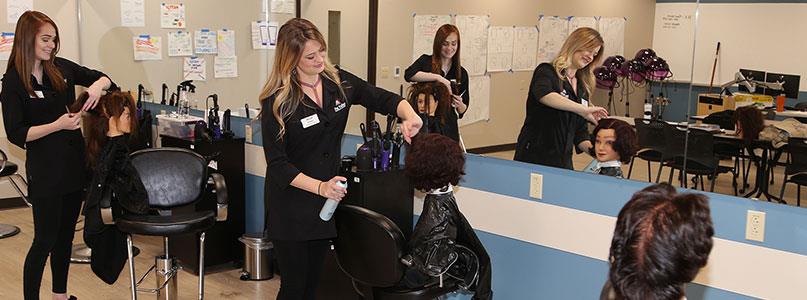 students learning cosmetology in hair salon using training mannequins