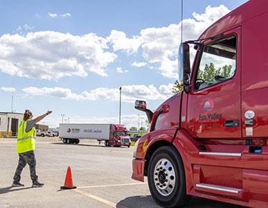 person in yellow safety vest directing Fox Valley Tech semi truck driver