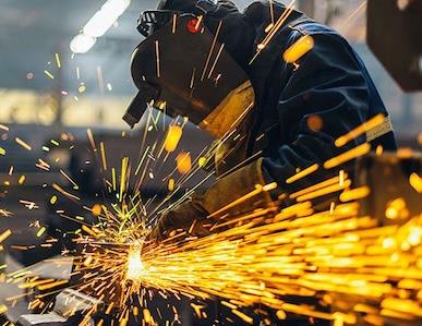 person using grinder in welding mask with sparks flying