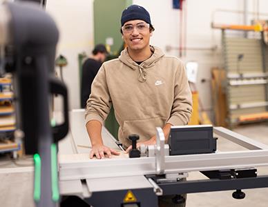 smiling man standing near woodworking equipment