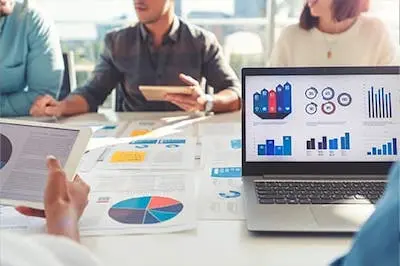 table of people on computers and looking at charts on paper