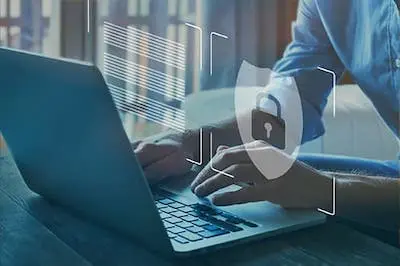 person on a laptop typing with security shield and padlock hovering over the keyboard