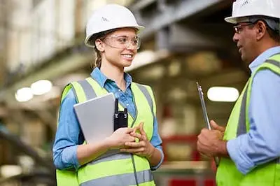 two safety employees in hardhats talking