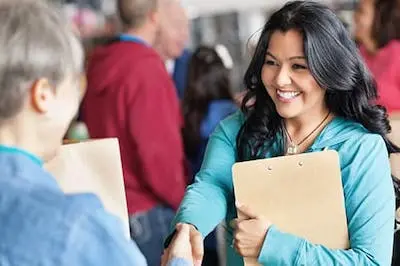 two people with clipboards shaking hands